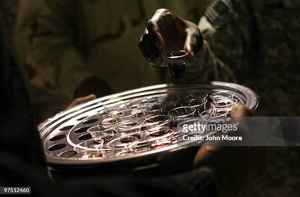 American soldiers take cups of grape juice while participating in communion during a Gospel church service March 7, 2010 at the Kandahar Air Field in...