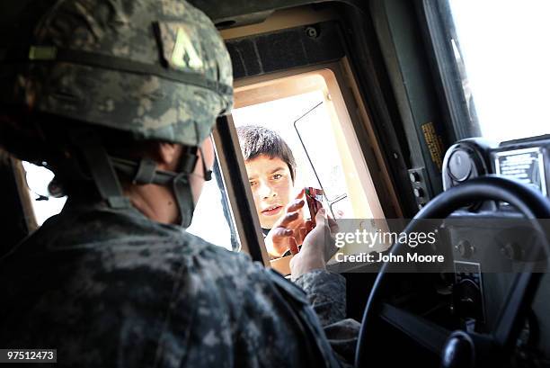 Chaplain's assistant gives candy to an Afghan child whilie traveling between bases to hold Catholic Mass on March 7, 2010 near the Kandahar Air Field...