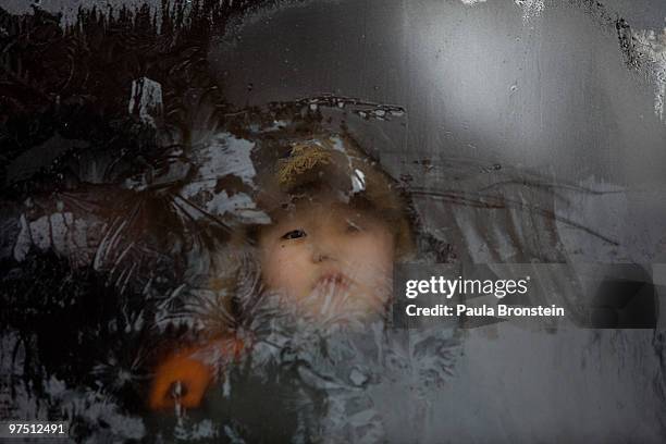 Mongolian boy looks out from a frosty window on a city bus on March 7, 2010 in Ulaan Baatar, Mongolia. Monglia is still experiencing one of the worst...