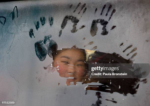 Mongolian girl looks out from a frosty window riding on a city bus March 6, 2010 in Ulaan Baatar, Mongolia. Monglia is still experiencing one of the...