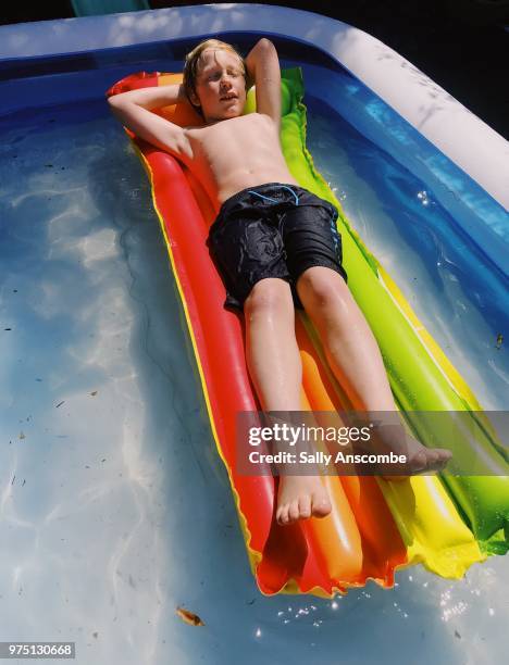 child sunbathing on a lilo - sally anscombe stock-fotos und bilder