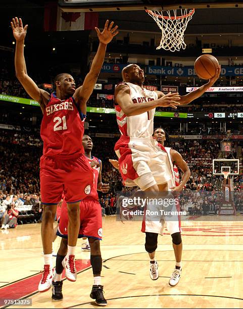 Jarrett Jack of the Toronto Raptors attempts the reverse layup under the net past defender Thaddeus Young of the Philadelphia 76ers during a game on...