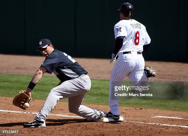 Nick Punto of the Minnisota Twins beats out a hit against first baseman Mark Teixeira of the New York Yankees at Lee County Sports Complex on March...