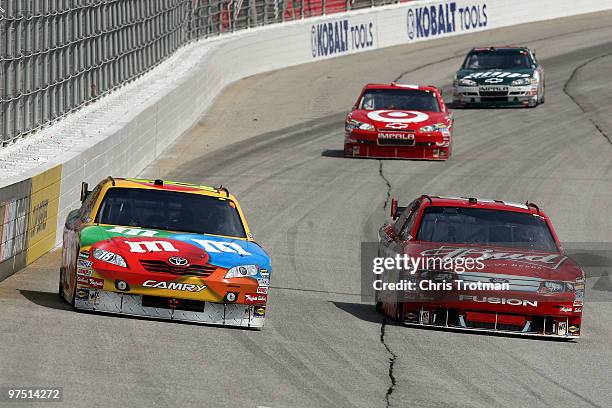 Kyle Busch, driver of the M&M's Toyota, races Kasey Kahne, driver of the Budweiser Ford, side by side ahead of Juan Pablo Montoya, driver of the...