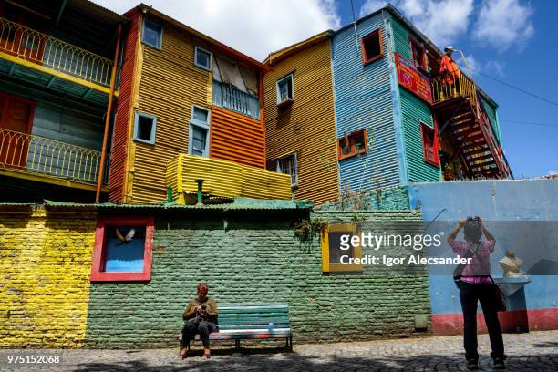 tourist taking pictures of a colorful buildings in caminito, buenos aires - moving down to seated position stock pictures, royalty-free photos & images