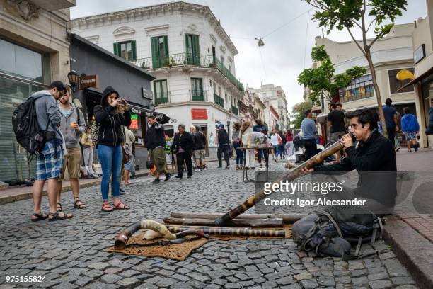 street performer playing didgeridoo in san telmo, buenos aires - moving down to seated position stock pictures, royalty-free photos & images