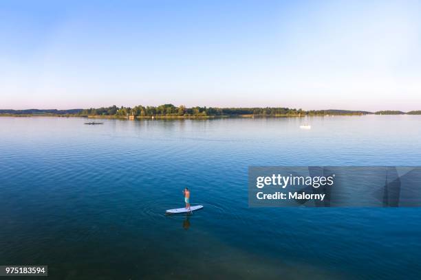 aerial view on young man paddle boarding on lake chiemsee. chiemsee, chiemgau, bavaria, germany - chiemsee stockfoto's en -beelden