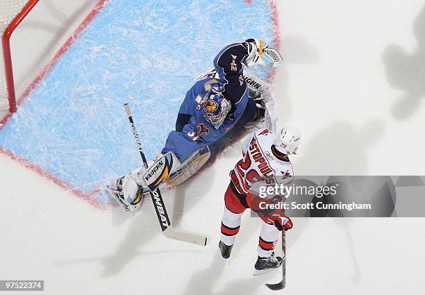 Ondrej Pavelec of the Atlanta Thrashers makes a save in front of Tom Kostopolous of the Carolina Hurricanes at Philips Arena on March 7, 2010 in...