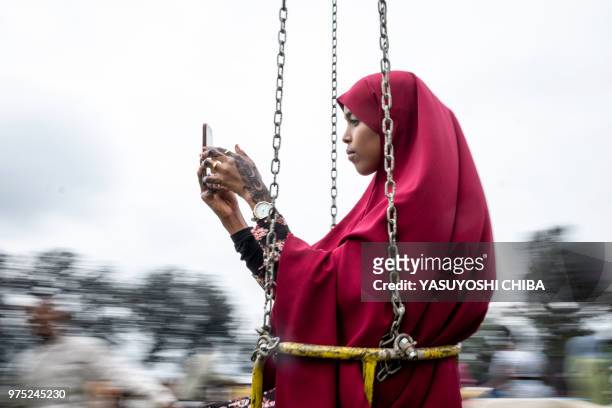 Kenyan Muslim woman takes a selfie as she enjoys a fairground ride on the cricket field at the Sir Ali Muslim Club in Nairobi, Kenya, on June 15,...
