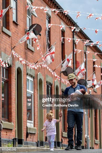 Year-old Lottie Rose Kenway holds hands with Stephen Mullane as he carries his 8-week-old daughter Hollie Mullane on Wales Street in Oldham, which...