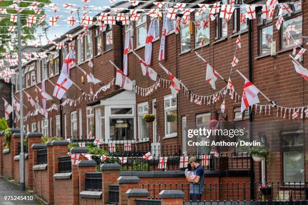 Stephen Mullane nurses his 8-week-old daughter Hollie Mullane in their front garden on Wales Street in Oldham, which local residents have re-named...