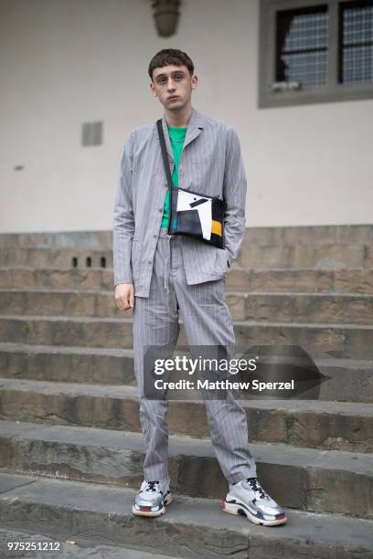 Guest is seen during the 94th Pitti Immagine Uomo wearing a grey suit with green shirt and cross-body bag on June 13, 2018 in Florence, Italy.