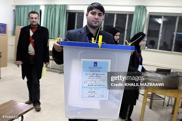 An Iraqi election staffer carries a sealed ballot box at the end of voting at a polling station in a Jordanian government school in Amman on March 7,...