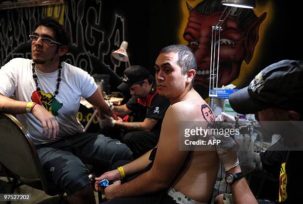 Tattooists work on their customers during the 6th International Tattoo Show in Buenos Aires on March 7, 2010. The exhibition draws participants from...