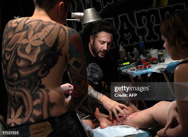 Tattooist speaks to two clients during the 6th International Tattoo Show in Buenos Aires on March 7, 2010. The exhibition draws participants from...