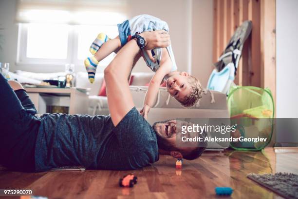 vater mit sohn im wohnzimmer spielen - raising baby stock-fotos und bilder