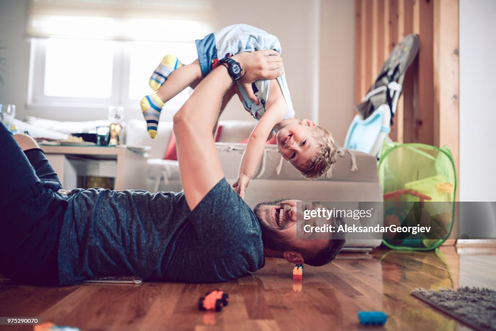 Father Playing With Baby Son In Living Room