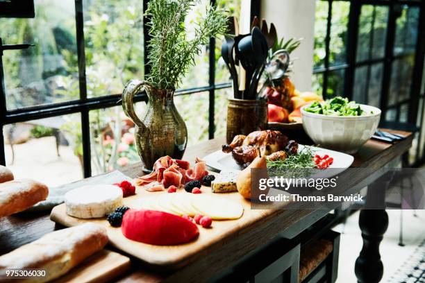 sideboard in kitchen set with appetizers roast chicken and salad before family celebration meal - estilismo culinário imagens e fotografias de stock