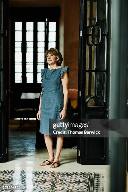 portrait of senior woman standing in home looking out window - true peoples celebration day one stock pictures, royalty-free photos & images