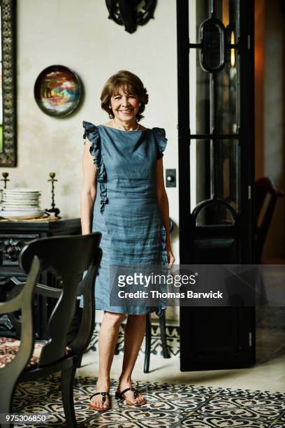 Portrait of smiling senior woman standing in dining room before family dinner party