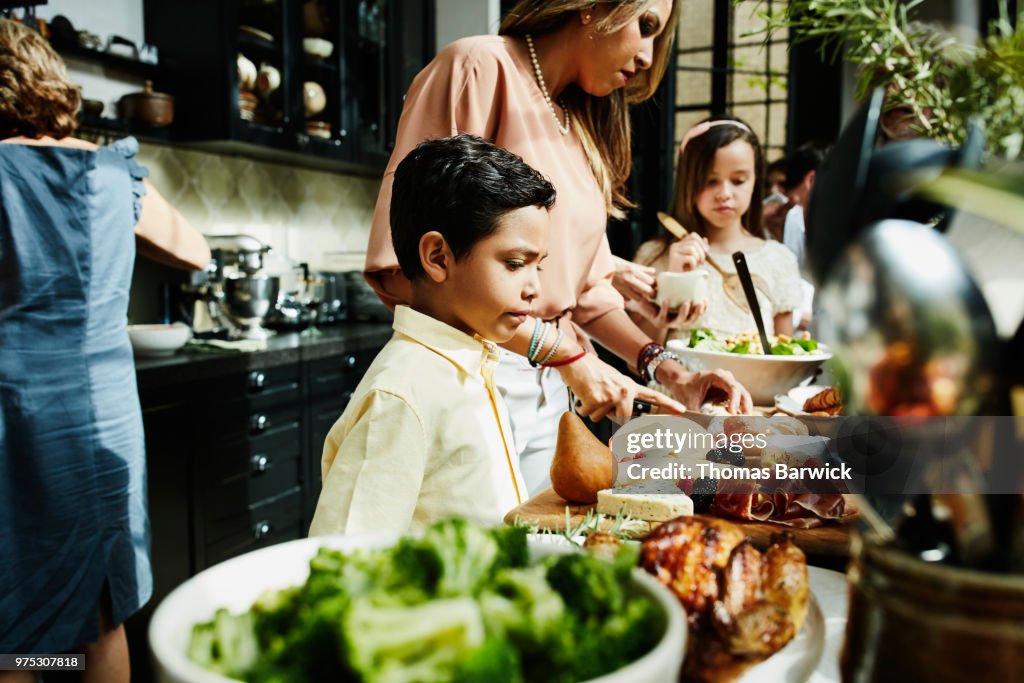 Young boy looking at food in kitchen set out for family dinner party