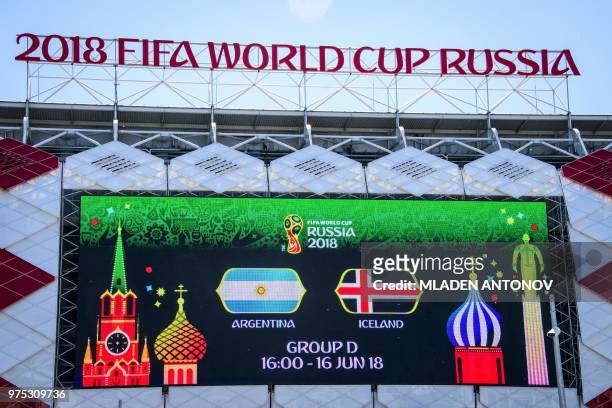 Picture taken on June 15, 2018 shows a giant screen announcing tomorrow's match and the 2018 FIFA World Cup sign on top of the Spartak football...