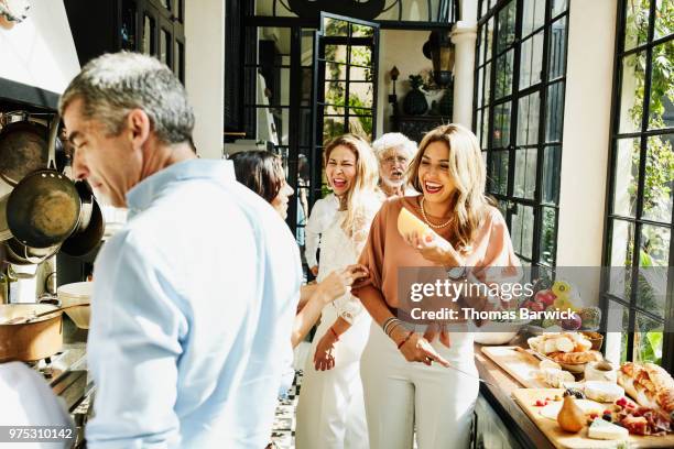 laughing family members preparing food in kitchen for celebration dinner - familienfest stock-fotos und bilder