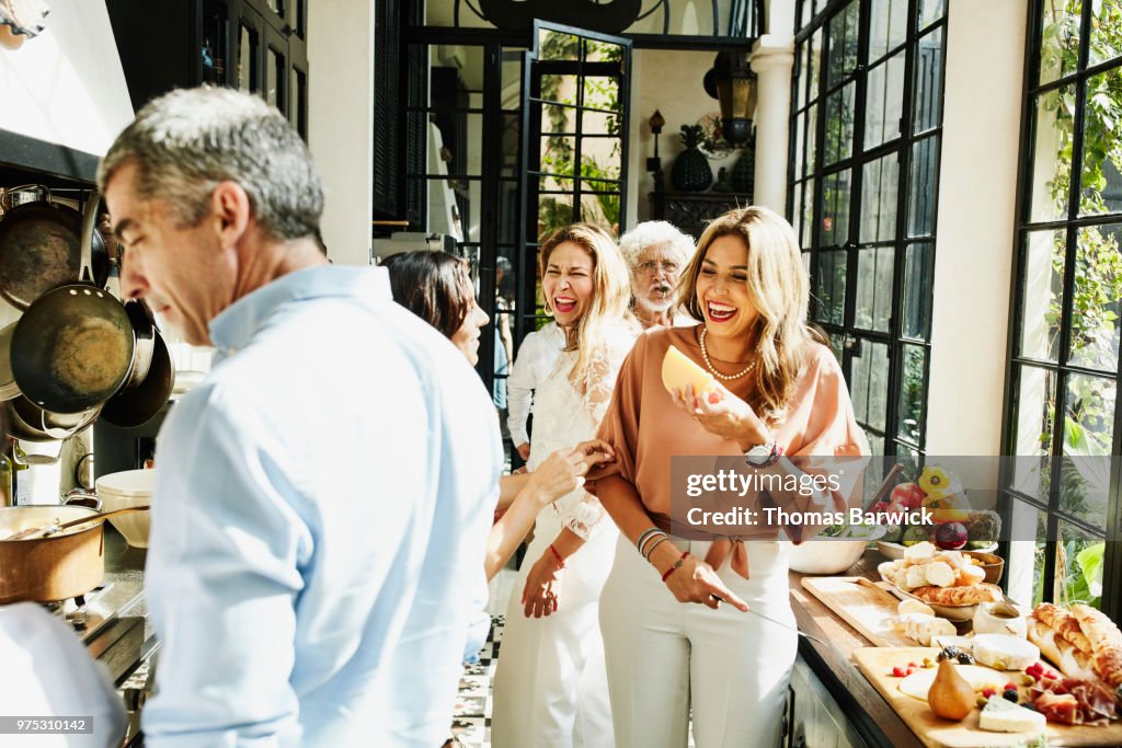 Laughing family members preparing food in kitchen for celebration dinner