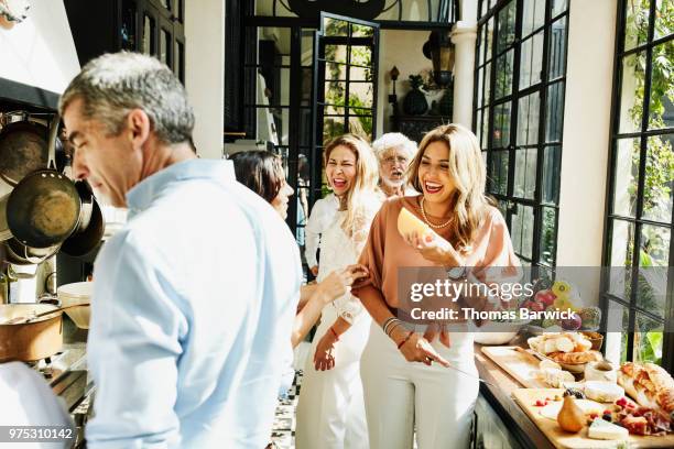 laughing family members preparing food in kitchen for celebration dinner - active seniors indoors stock pictures, royalty-free photos & images