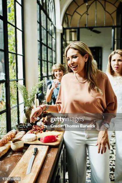 smiling woman preparing appetizers in kitchen for family celebration meal - 3 women senior kitchen stock pictures, royalty-free photos & images