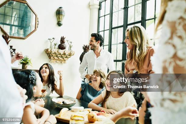 laughing multigenerational family gathered around dining room table sharing appetizers before birthday dinner - wealth stockfoto's en -beelden