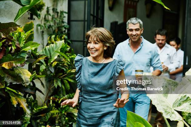 smiling grandmother walking into backyard during family dinner party - frau 50 garten stock-fotos und bilder