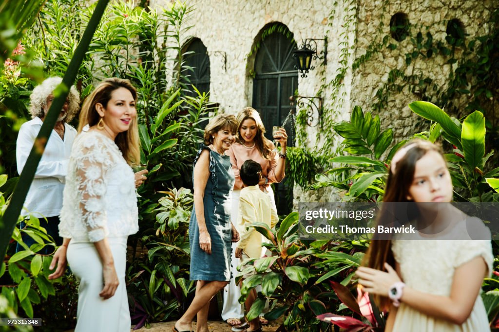 Multigenerational family hanging out together in backyard garden during dinner party