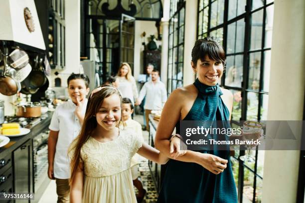 smiling aunt and niece walking through kitchen arm in arm during family dinner party - sobrina fotografías e imágenes de stock