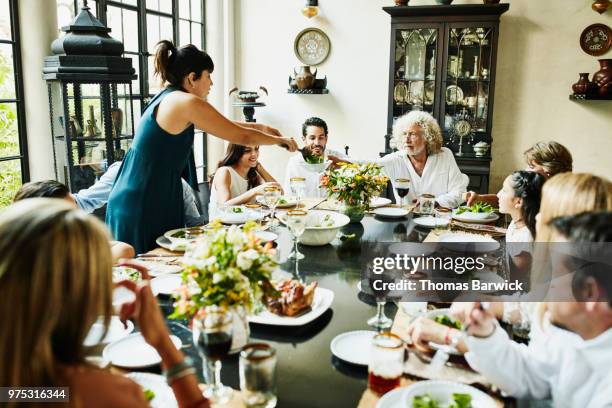 grandfather being served food at dining room table during multigenerational family dinner - dinner party menschen raum elegant stock-fotos und bilder