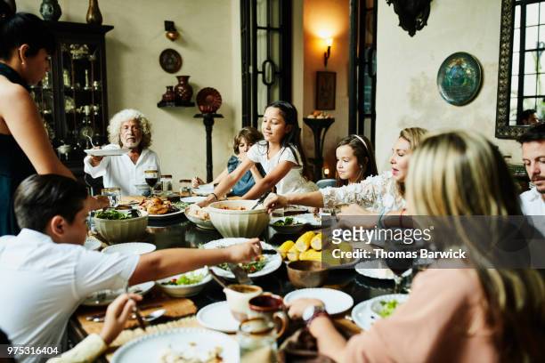 young girl bringing platter of bread to dining room table during family celebration meal - tischflächen aufnahme stock-fotos und bilder