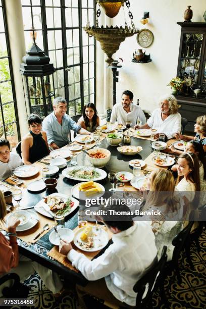 overhead view of multigenerational family gathered at dining room table for celebration meal - wealthy family inside home stock pictures, royalty-free photos & images