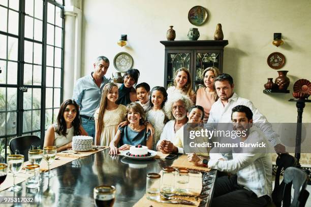 portrait of multigenerational family gathered in dining room during celebration dinner - multi generation family portrait stock pictures, royalty-free photos & images