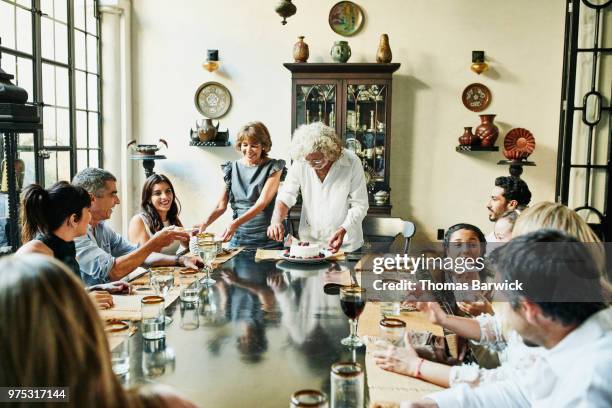 grandparents cutting and passing cake during family birthday dinner - passing giving photos et images de collection