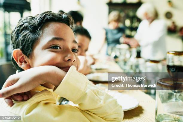 portrait of smiling young boy sitting at dining room table with family during birthday dinner - geburtstag 11 stock-fotos und bilder