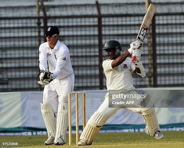 Bangladeshi cricketer Raquibul Hossain plays a shot as England cricketer Steve Davies looks on during the second day of the three-day long match...