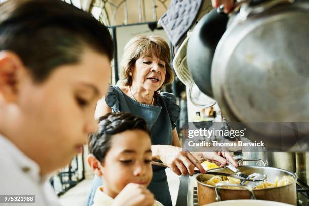 grandsons helping grandmother prepare food in kitchen for family dinner - granny stockfoto's en -beelden