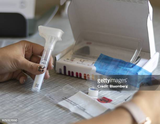 Reporter examines a 23andMe Inc. DNA genetic testing kit in Oakland, California, U.S., on Friday, June 8, 2018. The direct-to-consumer...