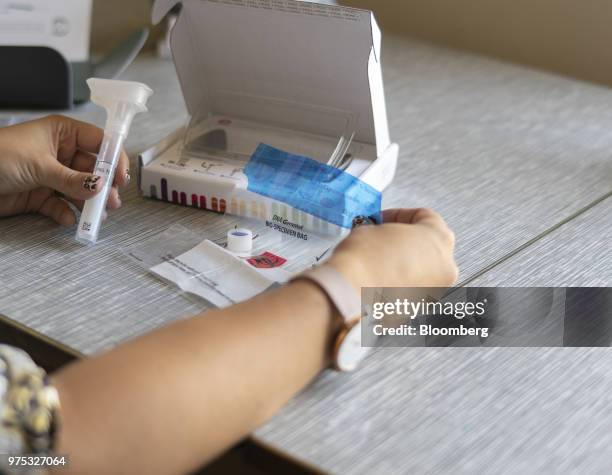 Reporter examines a 23andMe Inc. DNA genetic testing kit in Oakland, California, U.S., on Friday, June 8, 2018. The direct-to-consumer...