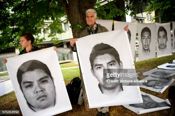 May 2018, Germany, Stuttgart: Weapons critics holding pictures of 43 students who were kidnapped in Mexico in 2014 and are thought to have been...