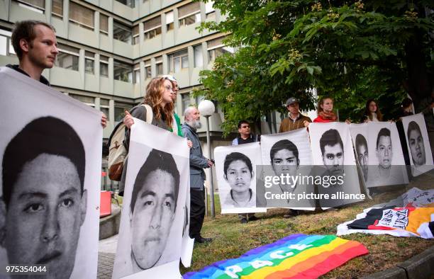 May 2018, Germany, Stuttgart: Weapons critics holding pictures of 43 students who were kidnapped in Mexico in 2014 and are thought to have been...