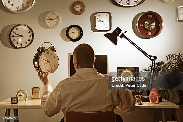 man sitting at desk surrounded by clocks - 時計職人 ストックフォトと画像