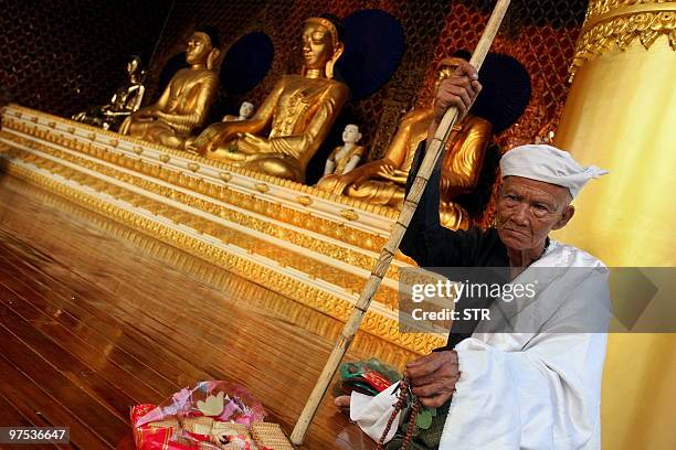 This picture taken on March 7, 2010 shows an elderly Myanmar devotee holding prayer beads as he sits in the courtyard of the Shwedagon pagoda in...