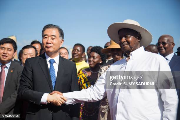 China's third vice prime minister, Wang Yang and Ugandas President Yoweri Museveni shake hands as they pose during the inauguration ceremony of the...