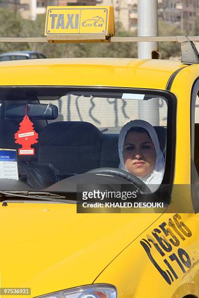 Egyptian taxi driver Ines Hassan waits for customers in her car in Cairo on March 6, 2010. The 36-year-old taxi driver is one of several women...